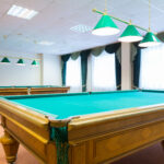 Two billiard tables in a room with windows